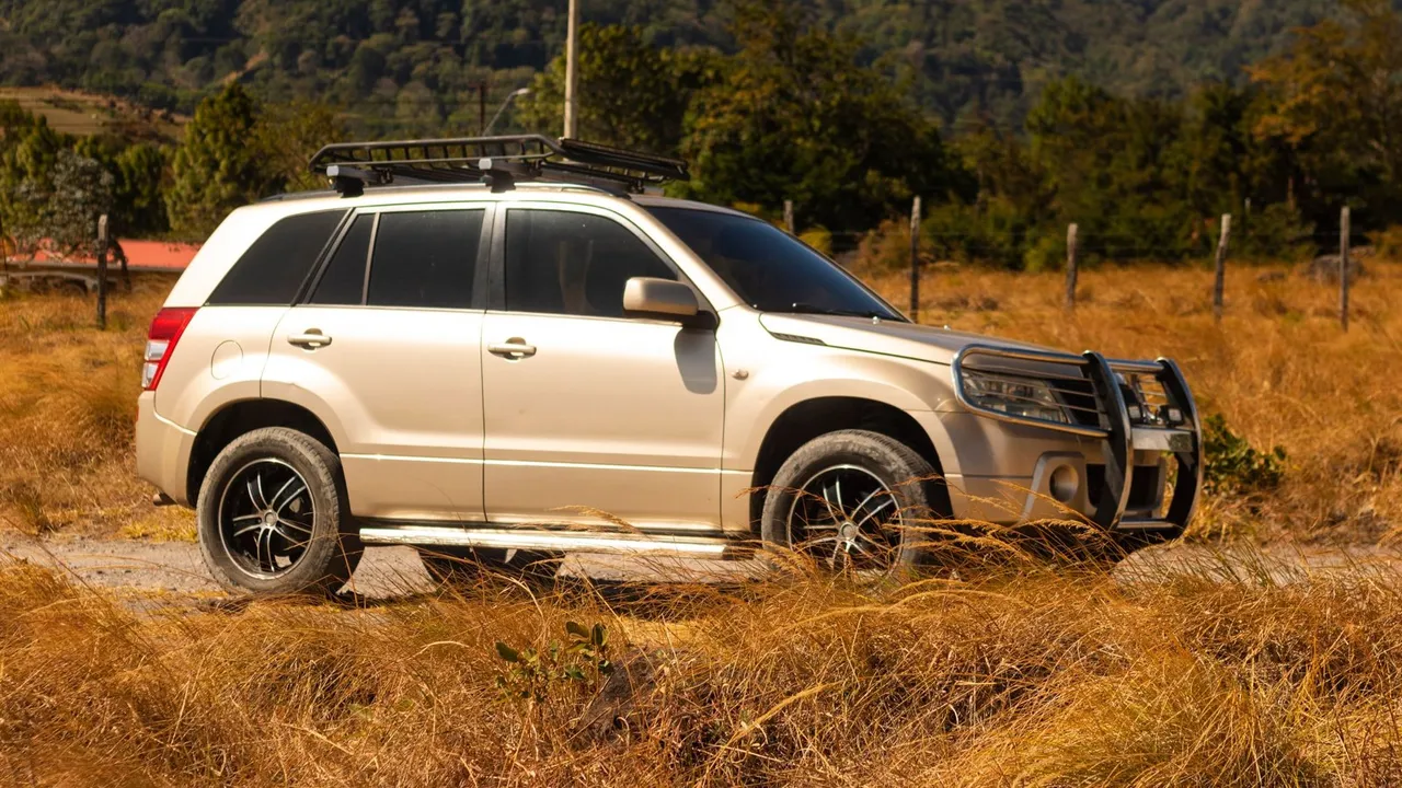 Suzuki Vitara compact blanc garé sur route de montagne, vue trois quarts avant, lumière naturelle